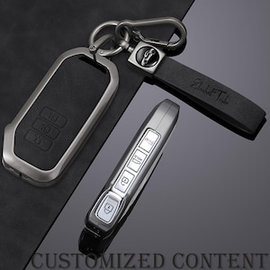 May include: A set of car keys and key accessories. The set includes a black leather key fob cover with silver trim, a silver car key, and a black leather key chain with the name "Elizabeth Taylor" engraved on it. The words "CUSTOMIZED CONTENT" are at the bottom.