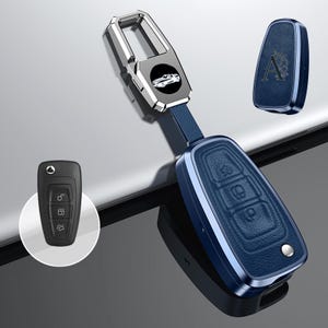 May include: A blue leather car key fob with a silver metal frame and a matching key cover. The key fob has three buttons and a silver accent. A small black car key is also shown.