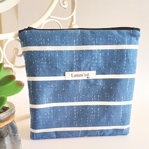 May include: A blue and white striped zippered pouch with the text "Lamm'ed" on a small label. The pouch is rectangular and appears to be made of fabric. The stripes are horizontal and white against a blue background.