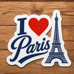 以下が含まれることがあります： 「I Paris」の文字がネイビーブルーの筆記体で書かれ、赤いハートとネイビーブルーのエッフェル塔のイラストが描かれた白いステッカー。ステッカーは木製の背景にあります。