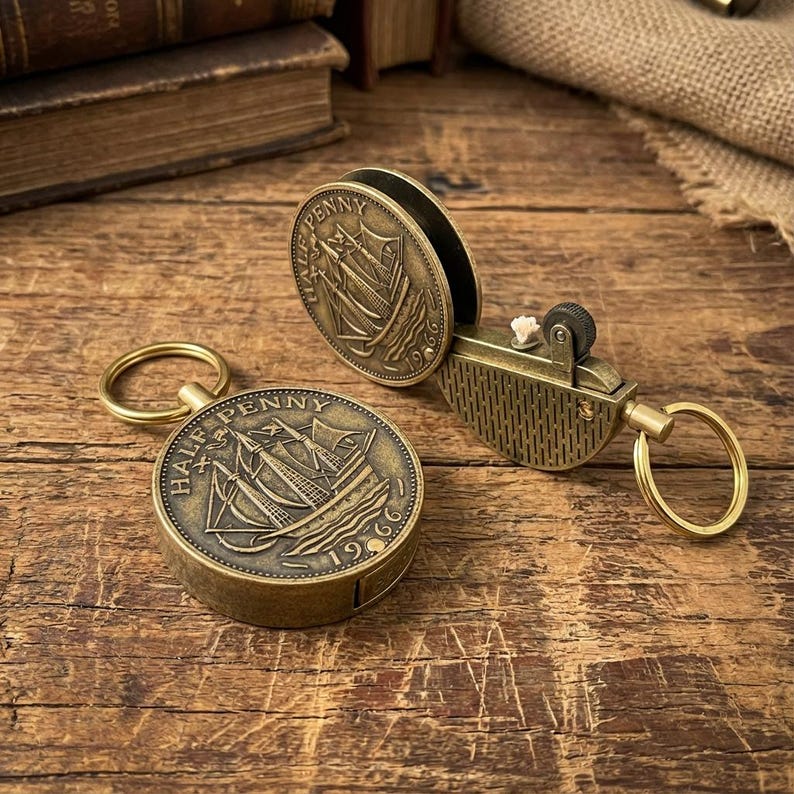 May include: Antique brass coin lighters and a coin case. The lighters and case feature a ship design and the text "HALF PENNY" and "PENNY" with the year "1966". The lighters have a key ring attachment.