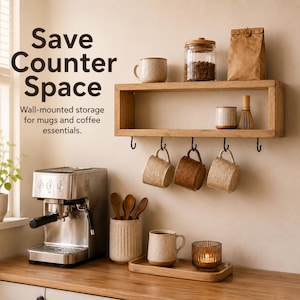 May include: A rectangular wooden wall-mounted shelf with five black metal hooks holding three ceramic mugs. The shelf displays a glass jar, a paper bag, and a small cup. Text reads: Save Counter Space. Wall-mounted storage for mugs and coffee essentials.
