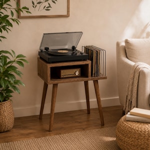 May include: A mid-century modern record player stand with a black turntable, a gold-colored stereo receiver, and a black record holder filled with vinyl records. The stand is made of wood and has tapered legs.