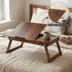 May include: A wooden bed tray with folding legs, featuring a dark brown finish. The tray has an adjustable top and a small compartment for a mug and coaster. The text "Add Personalization" is visible.