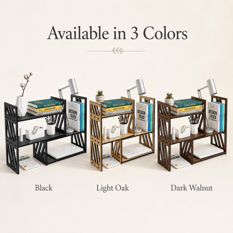 May include: Three wooden desktop organisers with a tiered, open-shelf design featuring diagonal side slats. The units are shown in black, light oak, and dark walnut finishes, each holding books, a small lamp, a plant, and office supplies.