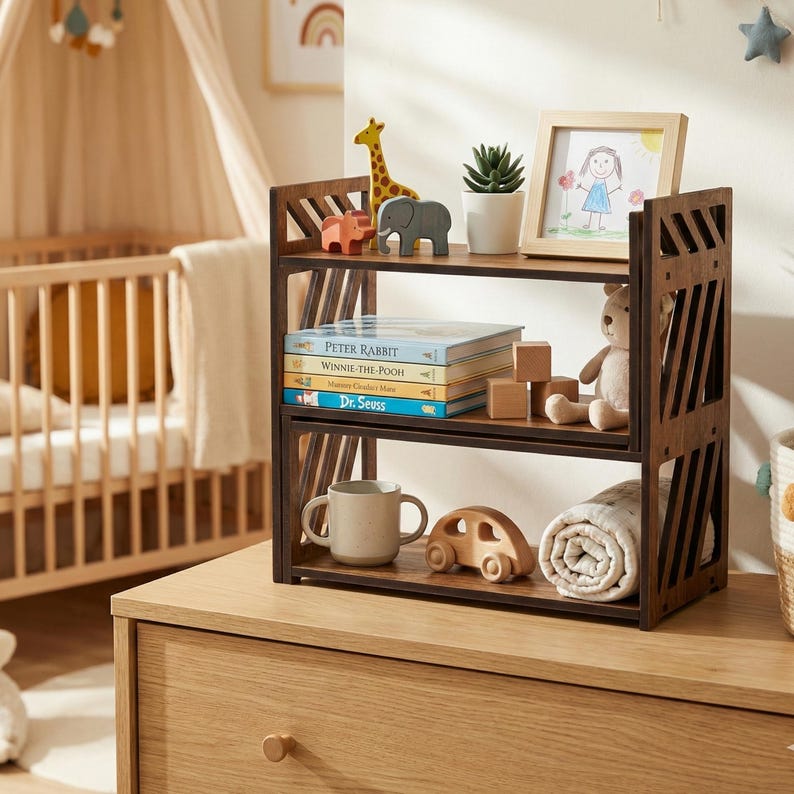 May include: A two-tier dark wood bookshelf with diagonal side slats. The top shelf holds a giraffe figurine, elephant figurine, small potted succulent, and a picture frame. The bottom shelf holds four children's books, wooden blocks, a mug, and a toy car.