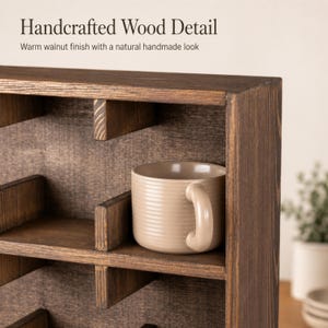May include: A dark brown wooden display shelf with multiple compartments and a warm walnut finish. The text Handcrafted Wood Detail and Warm walnut finish with a natural handmade look is visible. A beige ceramic mug sits on a shelf.