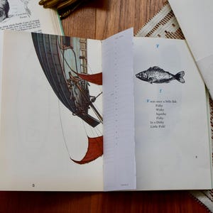 May include: Open book with illustrations of a sailboat and a fish. The text "F was once a little fish" is visible. A journal with the text "Home Bound Journal" is also present.