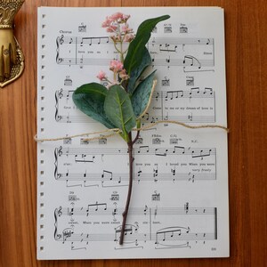 May include: A sheet of music with a floral arrangement on top. The music is for a song called "Love you" and includes lyrics like "I loved you, what you mean to me, very dearly".