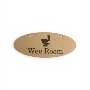 Könnte beinhalten: Ovales Holzschild mit dem Schriftzug "Wee Room" in braunen Buchstaben und einer Toilettengrafik. Das Schild hat zwei kleine Löcher zum Aufhängen. Ein humorvolles Schild für das Badezimmer.