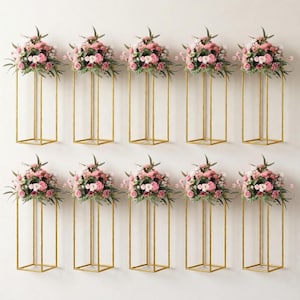 May include: Ten gold metal floral stands, each with a square base and top, supporting arrangements of pink and white flowers with green foliage. The stands are evenly spaced against a white background.