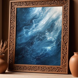 Op de afbeelding: Een ingelijst kunstwerk met een abstracte oceaanscène in blauwe en witte tinten. Het kunstwerk is ingelijst in een houten frame met ingewikkelde details. Het frame staat op een houten oppervlak.