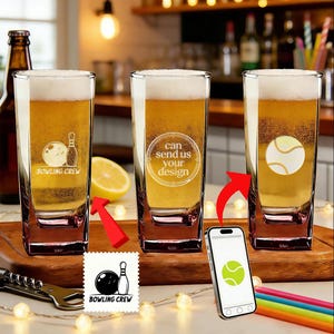 May include: Three clear pint glasses filled with beer and foam, each with a different design: a bowling ball and pin, a tennis ball, and the text "can send us your design". A smartphone displays a tennis ball graphic.