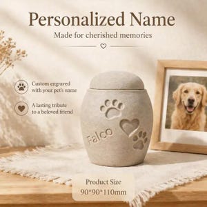 Puede incluir: Urna beige para mascotas con huellas de patas y un corazón, grabada con el nombre "Falco". Diseñada para recuerdos preciados. Tamaño del producto: 9 cm x 9 cm x 11 cm.