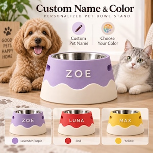 Pode incluir: Um suporte personalizado para tigela de animal com uma tigela de aço inoxidável, apresentando uma base ondulada creme e uma seção superior lavanda, vermelha ou amarela. O suporte exibe os nomes ZOE, LUNA ou MAX em letras brancas com alças.