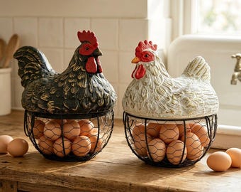 Puede incluir: Dos recipientes decorativos para huevos con forma de gallina. Uno es negro con cresta y barbilla rojas, el otro es blanco con detalles dorados y cresta y barbilla rojas. Cada uno tiene una cesta de alambre llena de huevos marrones.