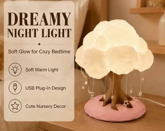 Puede incluir: Una lámpara de mesa con forma de árbol y copa en forma de nube que emite un brillo cálido. La base es rosa, el tronco es marrón y pequeños adornos blancos en forma de estrella cuelgan de la copa. El texto dice DREAMY NIGHT LIGHT, Soft Glow for Cozy Bedtime, Soft Warm Light, USB Plug-In Design y Cute Nursery Decor.