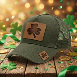 May include: Green baseball cap with a mesh back and a brown leather shamrock patch. A smaller shamrock patch is on the side. The cap is on a wooden surface with shamrock decorations and gold coins.