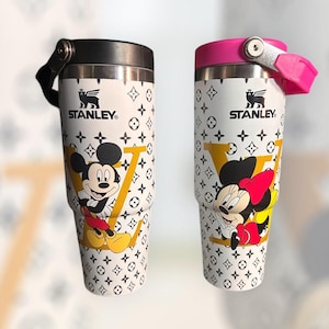 May include: A white ceramic mug with a black handle and the text "But First, Coffee" in a black, handwritten-style font. The mug is on a white surface.