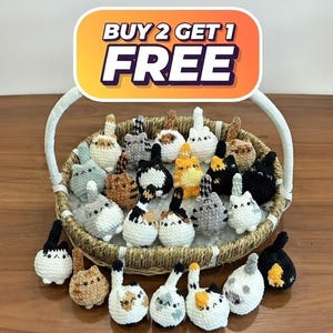 May include: A wicker basket filled with various handmade crochet cat figurines. The cats are white, gray, black, and orange, with different patterns. A sign above the basket reads "BUY 2 GET 1 FREE".