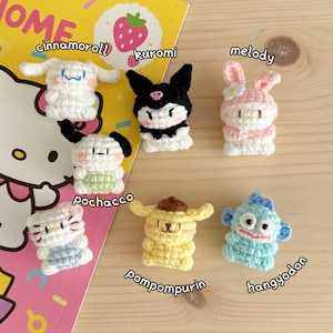 May include: A collection of seven crocheted character figures, including Cinnamoroll, Kuromi, Melody, Pochacco, Pompompurin, and Hangyodon. Each figure is crafted with detailed features and vibrant colors, set against a colorful background.