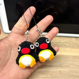 Puede incluir: Dos colgantes de pingüino hechos a mano, negros, blancos, rojos y amarillos. Cada colgante tiene un cuerpo negro, vientre blanco, pico rojo y pies amarillos. Están unidos a cordones negros con cierres plateados.