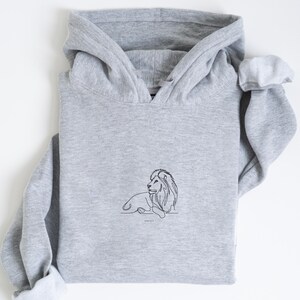 May include: A heather gray hoodie with a black line drawing of a lion. The lion is lying down with its head turned to the right. The text "John 10:10" is below the lion.