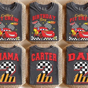 May include: Six gray t-shirts with racing-themed designs. The shirts feature text like "Carter's Pit Crew", "Birthday Boy", "Mama", "Carter", and "Dad". Each shirt has a red race car graphic or a number 2 with a checkered flag design.
