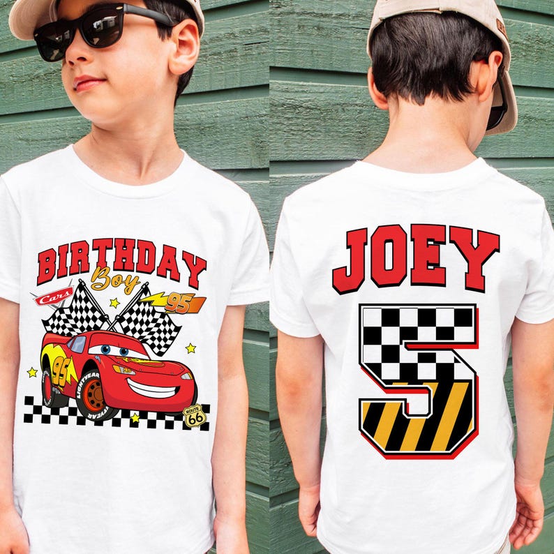 May include: White t-shirt featuring a red race car graphic with the text "BIRTHDAY Boy" and "95". The back of the shirt displays the name "JOEY" and the number "5" in a checkered and yellow design. The shirt is for a child.