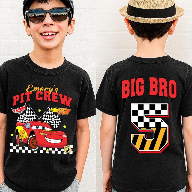 May include: Black t-shirt with a red race car graphic and the text "Emory's Pit Crew" on the front. The back of the shirt says "BIG BRO" with a number 5 design. The shirt is for a child.