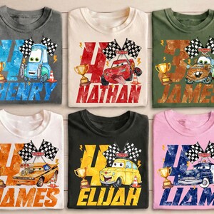 May include: Six colorful t-shirts featuring race car designs with names and the number 4. Each shirt has a different car graphic, checkered flags, a trophy, and a name: Henry, Nathan, James, Elijah, and Liam.