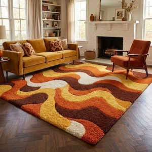May include: A shag rug with a retro design in shades of brown, orange, yellow, and white. The rug is in a living room with a mustard-colored sofa, an orange chair, and a fireplace. The rug's wavy pattern adds a vintage touch to the room.