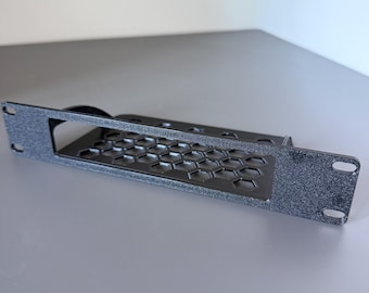 May include: A black, textured rack-mount panel featuring a rectangular cutout and a honeycomb-patterned ventilation grille. The metal component includes mounting holes on both ends, designed for standard equipment rack installation.