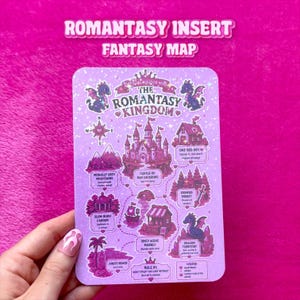 Op de afbeelding: Een rechthoekige paarse fantasiekaart met de titel The Romantasy Kingdom, voorzien van illustraties van een kasteel, draken, bergen en een bos. De kaart bevat tekstlabels voor locaties zoals Morally Grey Mountains, Enemies Forest en Spicy Scene Market, alles tegen een sterrenachtergrond.