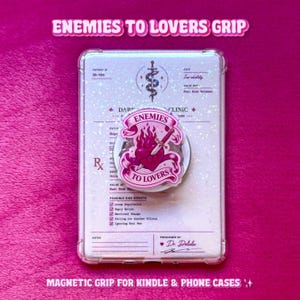 May include: A circular phone grip featuring a pink heart pierced by a dagger, surrounded by a banner with the text ENEMIES TO LOVERS. It is attached to a clear, holographic rectangular case printed with a medical prescription form design.