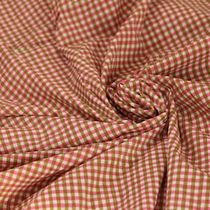 Könnte beinhalten: Ein Stoffstück mit einem kleinkarierten Vichy-Muster in abwechselnden Farbtönen von Rosa und Olivgrün. Das Textil ist in der Mitte gerafft, wodurch weiche, strahlenförmige Falten und Wellen entstehen, die das gleichmäßige Karomuster hervorheben.