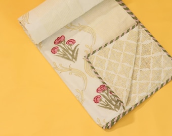 Könnte beinhalten: Ein gefaltetes Textil mit cremefarbener Basis, verziert mit rosa Blumenclustern und hellgelben geschwungenen Ranken. Die Rückseite zeigt ein sich wiederholendes geometrisches Blattmuster in Hellbraun, eingefasst von einer gestreiften grünen Borte.