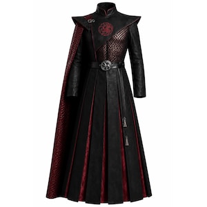 Può includere: Un cappotto nero e rosso scuro a maniche lunghe con collo alto, caratterizzato da un pannello frontale in rete testurizzata, un emblema circolare a forma di drago, una cintura abbinata con fibbia rotonda e un lungo mantello testurizzato.