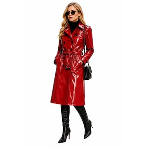 Pode incluir: Um trench coat vermelho brilhante, com design de abotoamento duplo e cinto na cintura. O casaco apresenta uma gola clássica e detalhes de botões. A pessoa está usando botas pretas e óculos de sol.