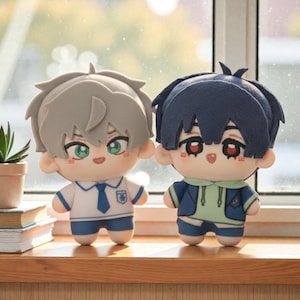 May include: Two plush dolls with anime-style features. One doll has gray hair, green eyes, and wears a white shirt with a blue tie. The other doll has dark blue hair, red eyes, and wears a blue jacket over a green hoodie. Both dolls have small blue shorts.