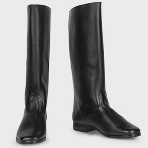 Könnte beinhalten: Zwei schwarze Reitstiefel. Die Stiefel sind hoch, reichen bis zum Knie, mit glatter, glänzender Oberfläche. Sie haben ein klassisches Design mit runder Spitze und kleinem Absatz. Die Stiefel sind aus lederähnlichem Material.