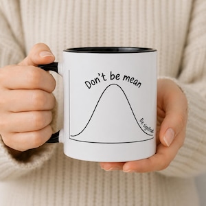 Op de afbeelding: Witte keramische mok met een zwarte binnenkant en handvat. De mok heeft de tekst "Don't be mean" boven een klokvormige grafiek, met "Be significant" eronder. De mok wordt door een persoon vastgehouden.