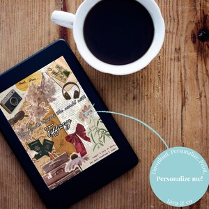 May include: A digital tablet shows a travel-themed design with illustrations of a camera, headphones, and luggage. The text "This Kindle travels the world with Tiffany" is visible. A cup of coffee sits nearby on a wooden surface.