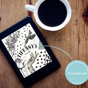 May include: A black e-reader shows a black and white graphic with roses, a tattoo gun, and a hand with tattoos. The text "TIFFANY'S kindle" is featured. A white coffee cup sits nearby on a wooden surface.