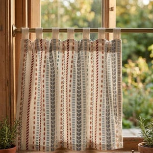 Peut inclure: Rideau à motifs avec un fond neutre et des rayures verticales grises et rouille. Le rideau est suspendu à une tringle en laiton dans un cadre de fenêtre en bois. Le motif présente un motif répétitif de flèches et de points.