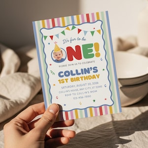 May include: A colourful birthday invitation with the text "It's fun to be ONE!" and "Collin's 1st Birthday." The invitation features a photo of a baby wearing a party hat, along with decorative stars and a striped border. The invitation is held in a hand.