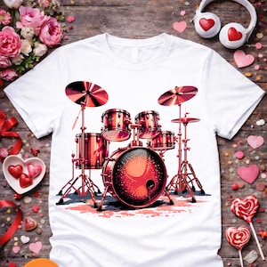 May include: White t-shirt with a red and black drum kit graphic. The illustration shows a bass drum, snare drums, cymbals, and stands. The design is a stylized graphic representation of a drum kit.
