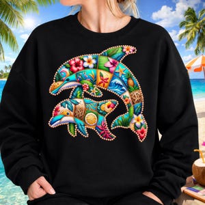 May include: Black sweatshirt featuring a colorful, patchwork design of two dolphins. The dolphins are adorned with tropical flowers, waves, and fruit. The design is outlined with small, dotted details, creating a vibrant and eye-catching image.