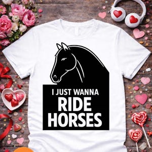 May include: White t-shirt featuring a black horse head graphic and the text "I JUST WANNA RIDE HORSES" in white. The design is on a black rectangular background. The shirt is a classic crew neck style.