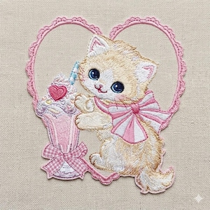 May include: Embroidered patch of a kitten with large blue eyes, wearing a pink bow, and holding a pink milkshake. The kitten is set against a pink heart-shaped frame. The patch has a detailed, textured design.
